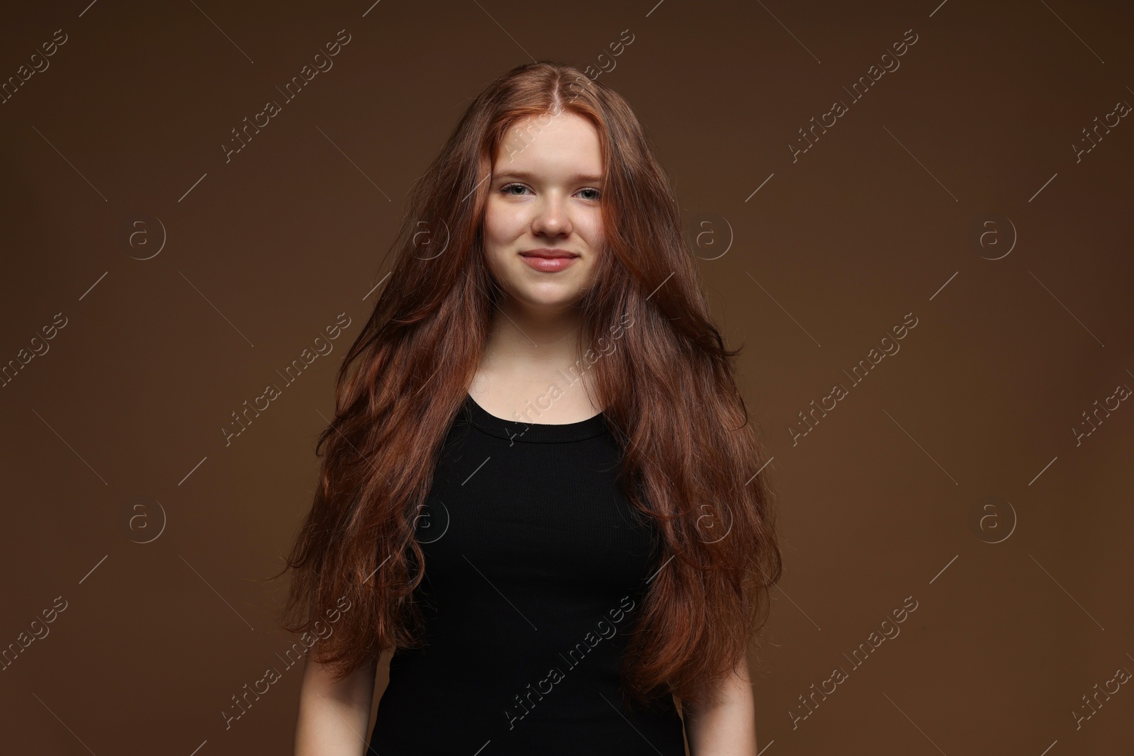 Portrait of beautiful teenage girl with healthy wavy hair on brown background Photo of Portrait of beautiful teenage girl with healthy wavy hair on brown background