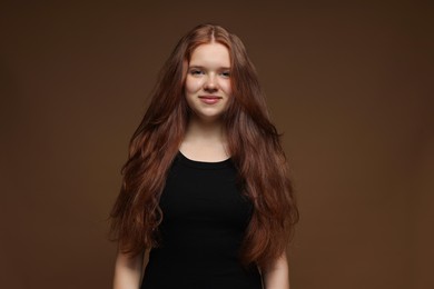 Photo of Portrait of beautiful teenage girl with healthy wavy hair on brown background