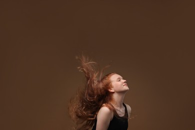 Photo of Teenage girl with healthy wavy hair on brown background