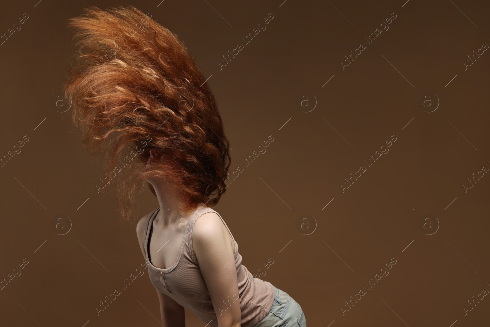 Teenage girl with healthy wavy hair on brown background. Space for text Photo of Teenage girl with healthy wavy hair on brown background. Space for text