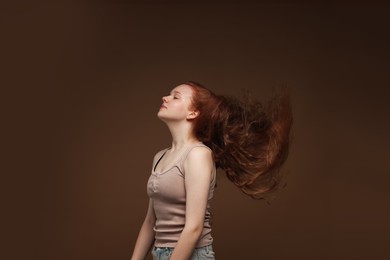 Photo of Teenage girl with healthy wavy hair on brown background