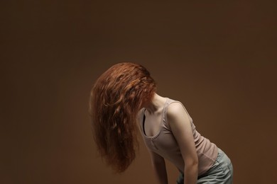 Photo of Teenage girl with healthy wavy hair on brown background