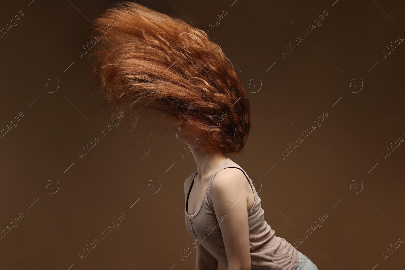Teenage girl with healthy wavy hair on brown background Photo of Teenage girl with healthy wavy hair on brown background