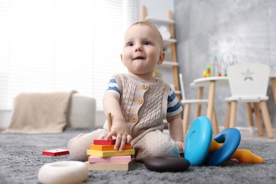 Photo of Cute little baby playing with toys in room