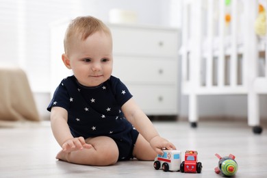 Photo of Cute little baby playing with toys in room