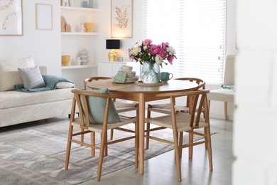 Photo of Dining table with beautiful flowers and dishware in room. Interior design