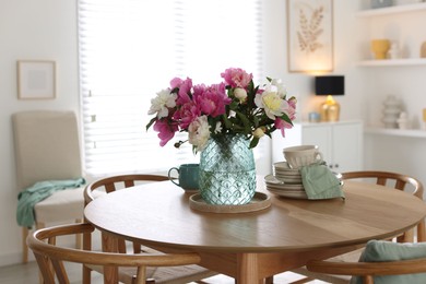 Photo of Dining table with beautiful flowers and dishware in room. Interior design