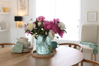 Photo of Dining table with beautiful flowers and dishware in room. Interior design