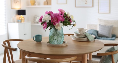 Photo of Dining table with beautiful flowers and dishware in room. Interior design