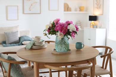 Photo of Dining table with beautiful flowers and dishware in room. Interior design
