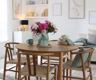 Photo of Dining table with beautiful flowers and dishware in room. Interior design