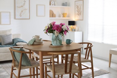 Photo of Dining table with beautiful flowers and dishware in room. Interior design