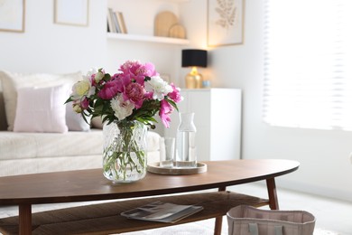 Photo of Bouquet of beautiful peonies and water on coffee table indoors. Interior design