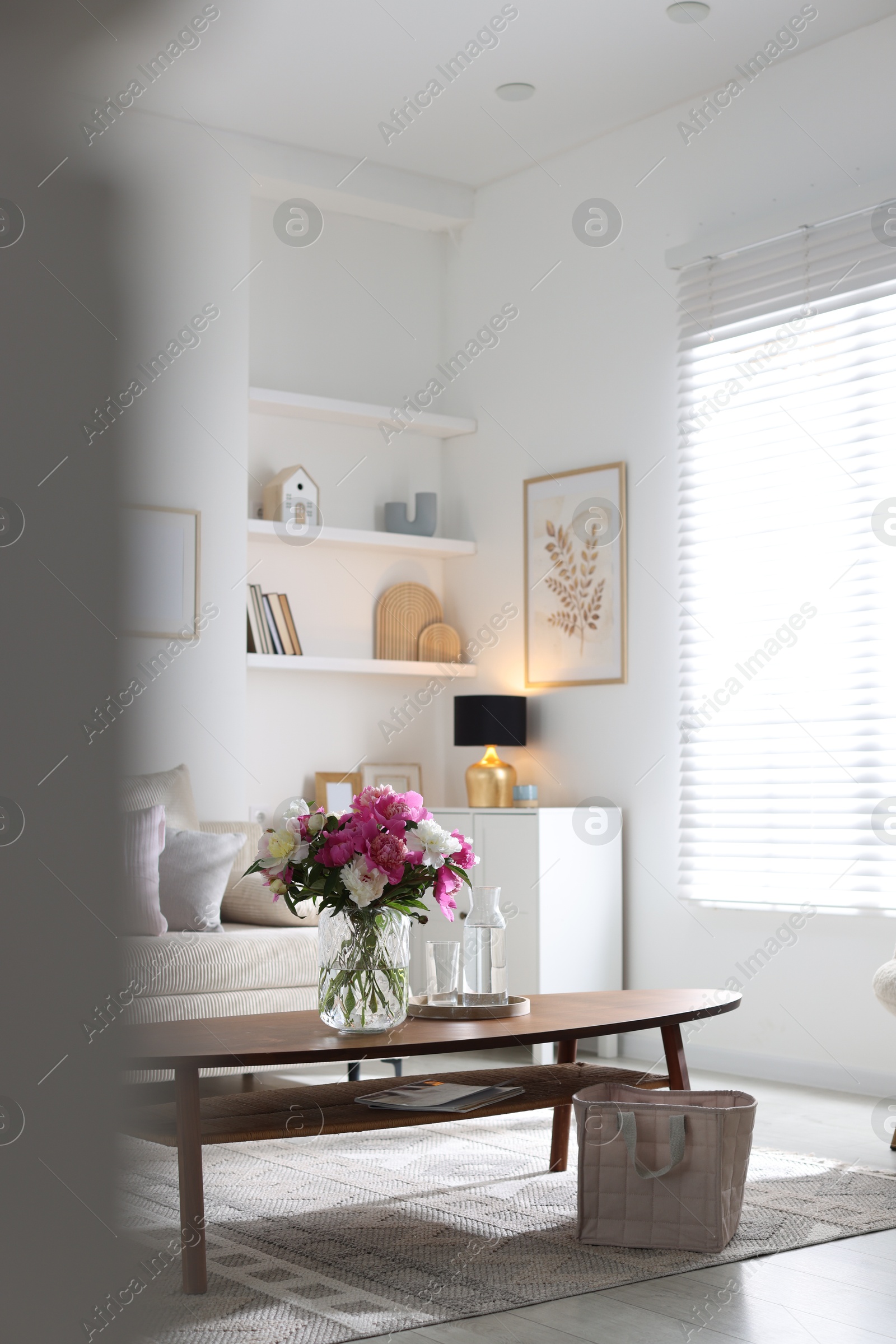Bouquet of beautiful peonies and water on coffee table indoors, space for text. Interior design Photo of Bouquet of beautiful peonies and water on coffee table indoors, space for text. Interior design