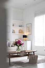 Photo of Bouquet of beautiful peonies and water on coffee table indoors, space for text. Interior design