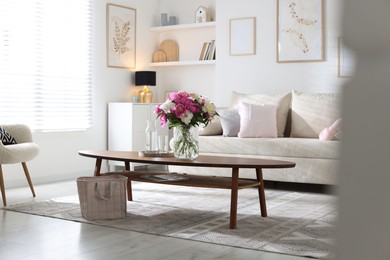 Photo of Bouquet of beautiful peonies and water on coffee table indoors. Interior design