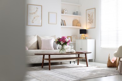 Photo of Bouquet of beautiful peonies and water on coffee table indoors. Interior design