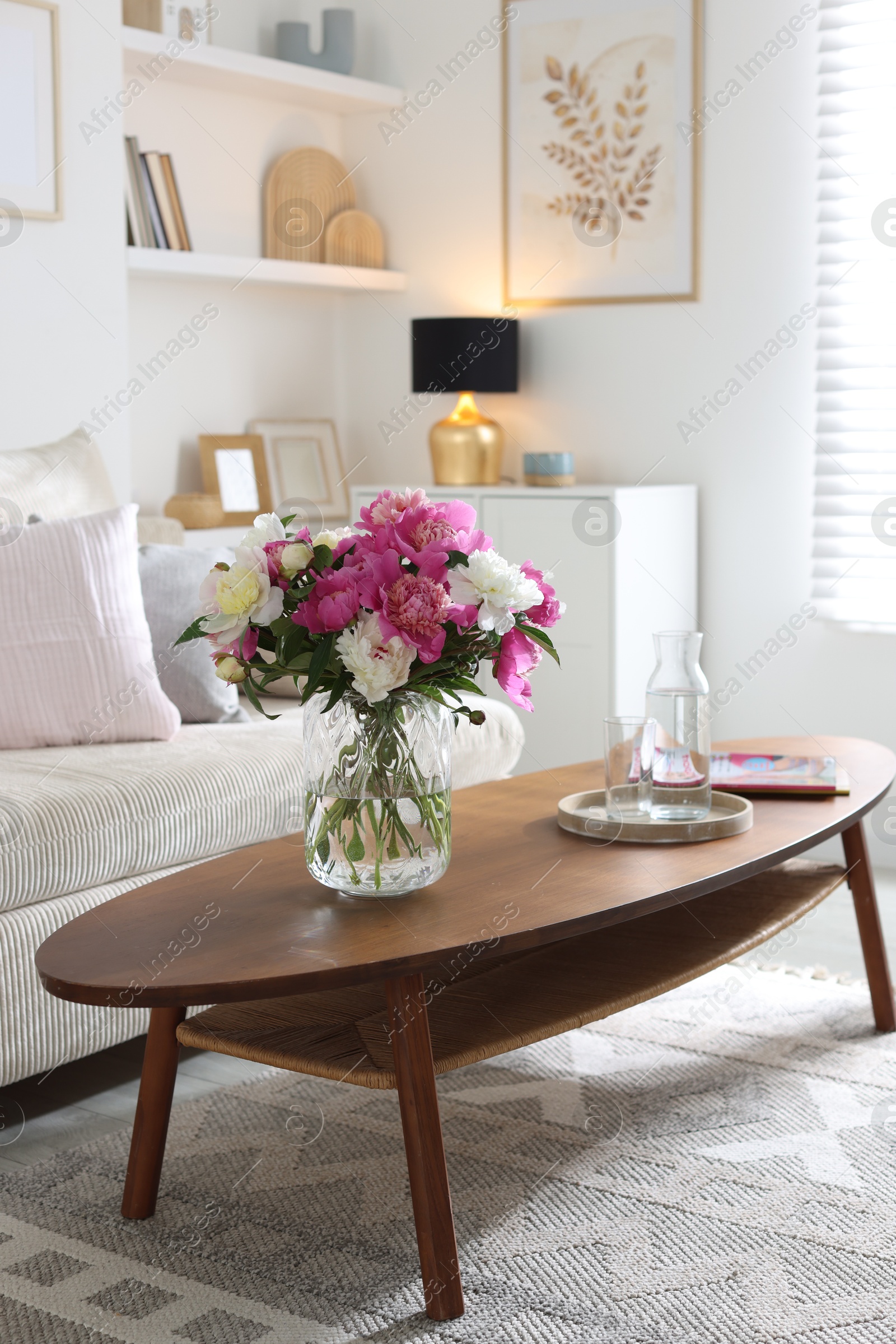 Bouquet of beautiful peonies and water on coffee table indoors, space for text. Interior design Photo of Bouquet of beautiful peonies and water on coffee table indoors, space for text. Interior design
