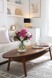 Photo of Bouquet of beautiful peonies and water on coffee table indoors, space for text. Interior design
