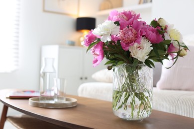 Photo of Bouquet of beautiful peonies and water on coffee table indoors, closeup. Interior design