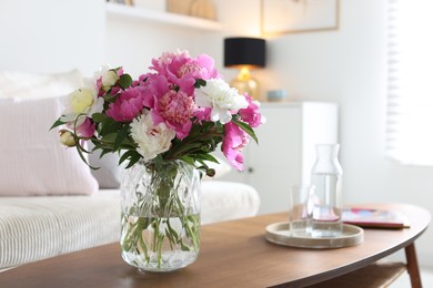 Photo of Bouquet of beautiful peonies and water on coffee table indoors. Interior design