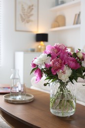 Photo of Bouquet of beautiful peonies and water on coffee table indoors. Interior design