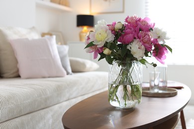 Photo of Bouquet of beautiful peonies and water on coffee table indoors. Interior design