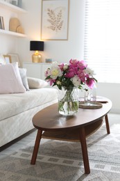 Photo of Bouquet of beautiful peonies and water on coffee table indoors. Interior design