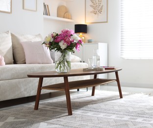 Photo of Bouquet of beautiful peonies and water on coffee table indoors. Interior design