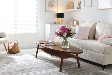 Photo of Bouquet of beautiful peonies and water on coffee table indoors, space for text. Interior design