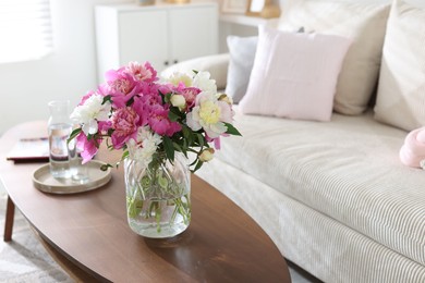 Photo of Bouquet of beautiful peonies and water on coffee table indoors, space for text. Interior design
