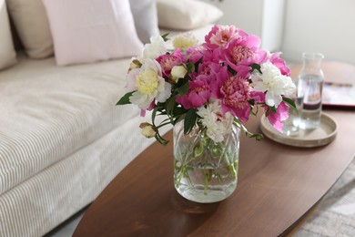 Photo of Bouquet of beautiful peonies and water on coffee table indoors, closeup with space for text. Interior design