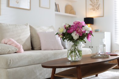 Photo of Bouquet of beautiful peonies and water on coffee table indoors, space for text. Interior design