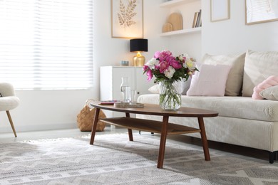 Photo of Bouquet of beautiful peonies and water on coffee table indoors, space for text. Interior design