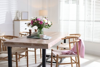 Photo of Dining table with beautiful flowers and dishware in room, space for text. Interior design