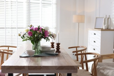 Photo of Dining table with beautiful flowers and dishware in room. Interior design