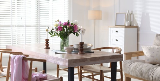 Photo of Dining table with beautiful flowers and dishware in room. Interior design