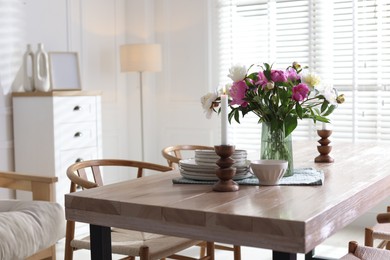 Photo of Dining table with beautiful flowers and dishware in room. Interior design