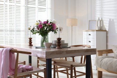 Photo of Dining table with beautiful flowers and dishware in room. Interior design