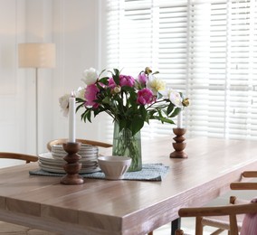 Photo of Dining table with beautiful flowers and dishware in room. Interior design