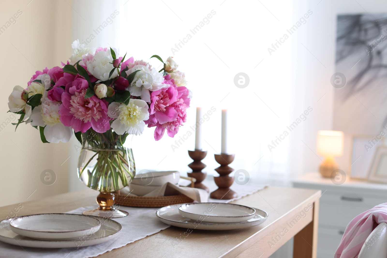 Beautiful table setting with bouquet of peonies in dining room, closeup. Space for text Photo of Beautiful table setting with bouquet of peonies in dining room, closeup. Space for text