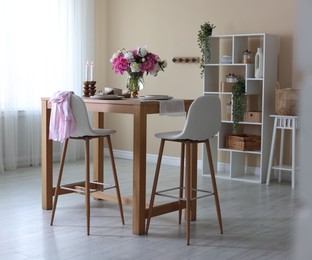 Photo of Beautiful table setting with bouquet of peonies in dining room. Interior design