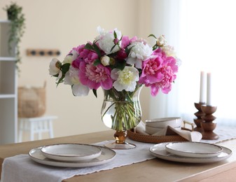 Photo of Beautiful table setting with bouquet of peonies in dining room, closeup