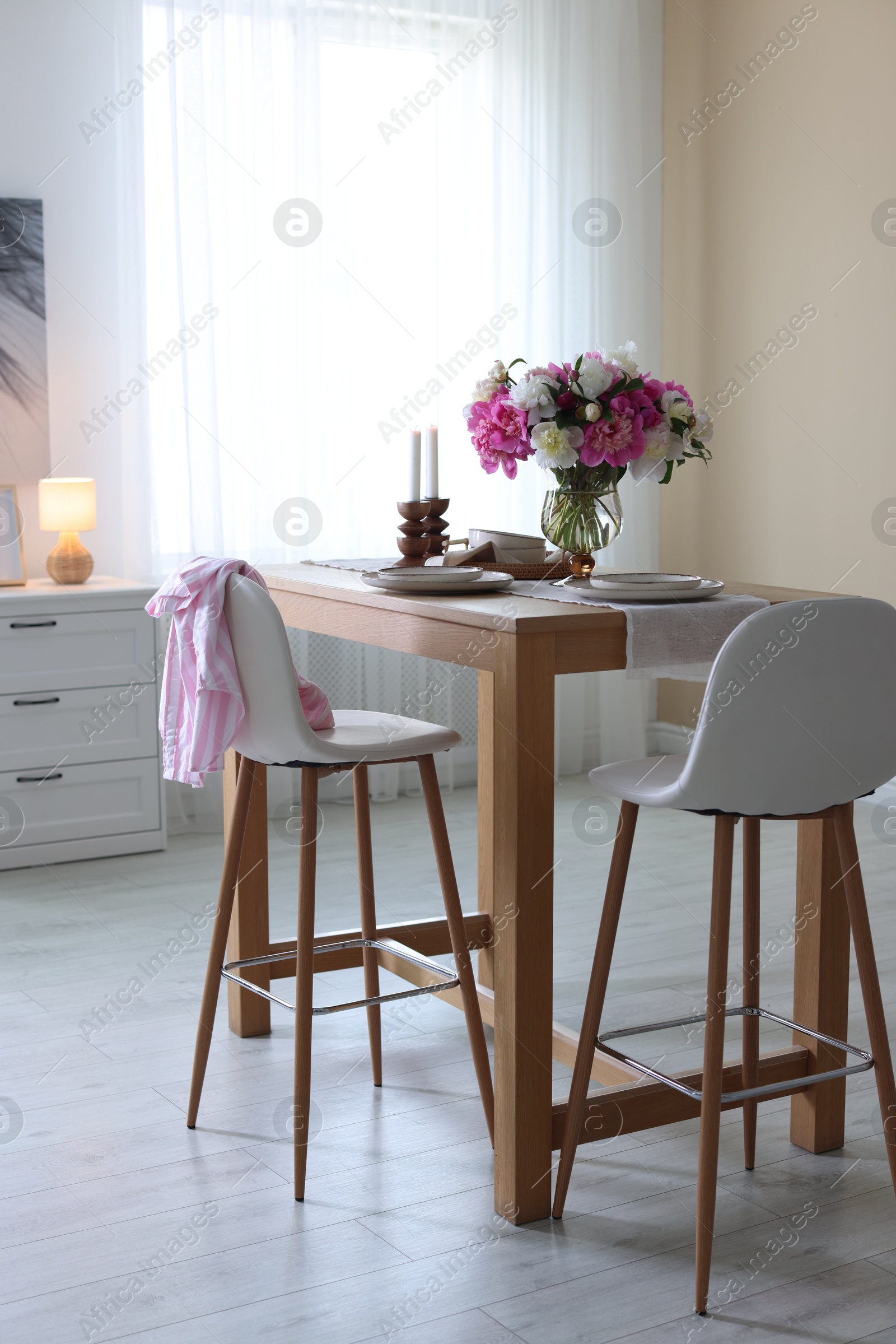 Beautiful table setting with bouquet of peonies in dining room. Interior design Photo of Beautiful table setting with bouquet of peonies in dining room. Interior design