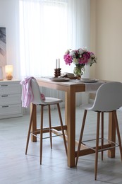 Photo of Beautiful table setting with bouquet of peonies in dining room. Interior design