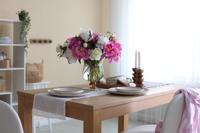 Photo of Beautiful table setting with bouquet of peonies in dining room. Interior design