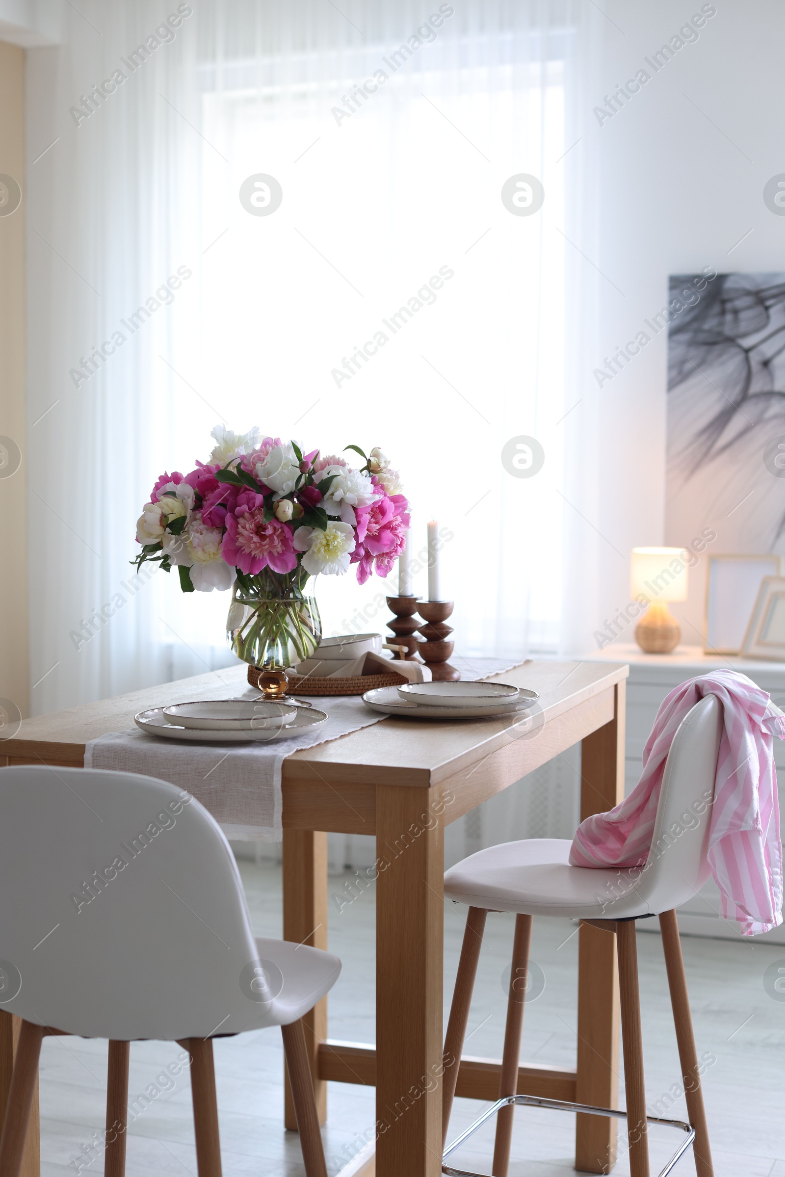 Beautiful table setting with bouquet of peonies in dining room. Interior design Photo of Beautiful table setting with bouquet of peonies in dining room. Interior design