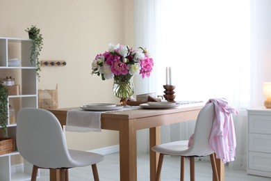 Photo of Beautiful table setting with bouquet of peonies in dining room. Interior design