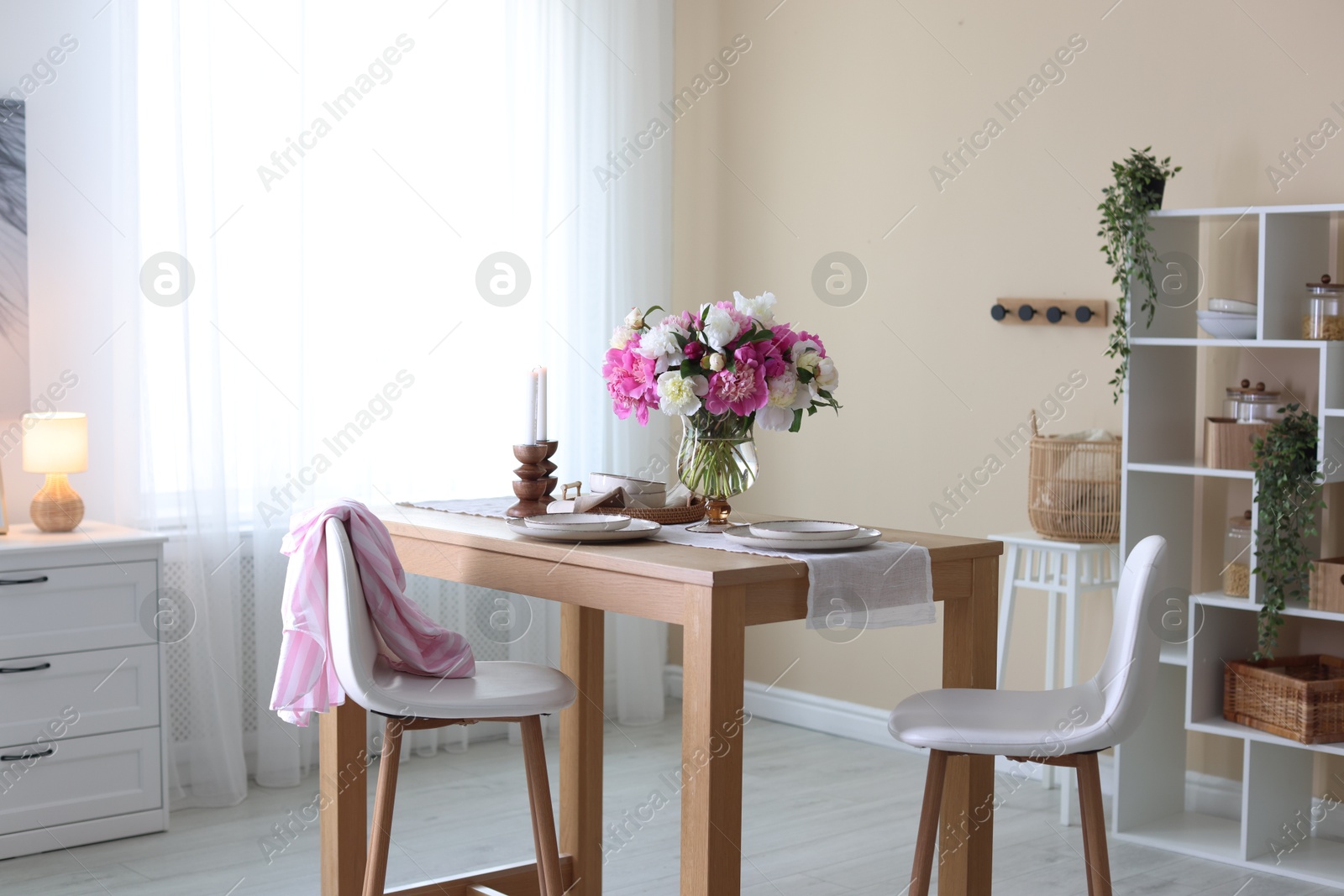 Beautiful table setting with bouquet of peonies in dining room. Interior design Photo of Beautiful table setting with bouquet of peonies in dining room. Interior design