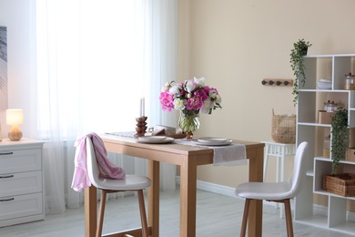 Photo of Beautiful table setting with bouquet of peonies in dining room. Interior design